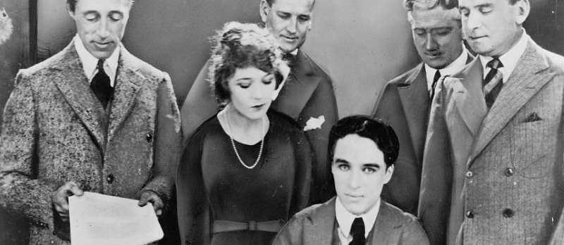 Fotomontage: D. W. Griffith, Mary Pickford, Charlie Chaplin, Douglas Fairbanks und Anwälte bei der Unterzeichnung des Gründungsvertrags von United Artists